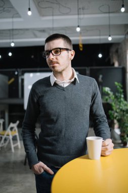 Masada duran ve elinde kupa tutan genç adam.