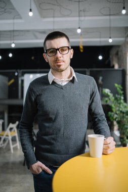 Elinde kahve fincanı olan sakallı bir işçi.