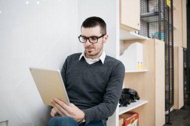 Ofis çalışanı elinde tabletle oturuyor.