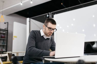 İşletme koçu derse hazırlanırken dizüstü bilgisayarda yazıyor.