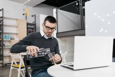 Ofis çalışanı bardağa su dolduruyor.