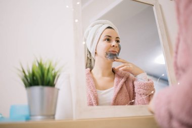 Yüzüne maske takan bir kadının ayna yansıması.