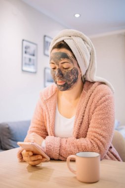 Akıllı telefonunu kullanarak kömür maskeli bir kız.