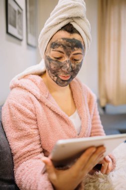 Kanepede otururken elinde tablet tutan bir kadın.