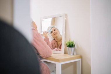 Türban takan mutlu bir kız cilt spatulası kullanarak yüzünü parçalıyor.