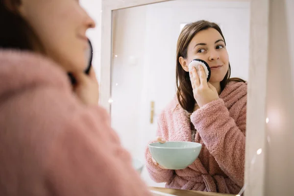 Sonriente chica quitando el maquillaje en el espejo — Foto de Stock