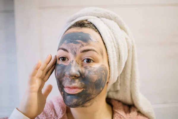 Chica con máscara de barro tocando su cara — Foto de Stock