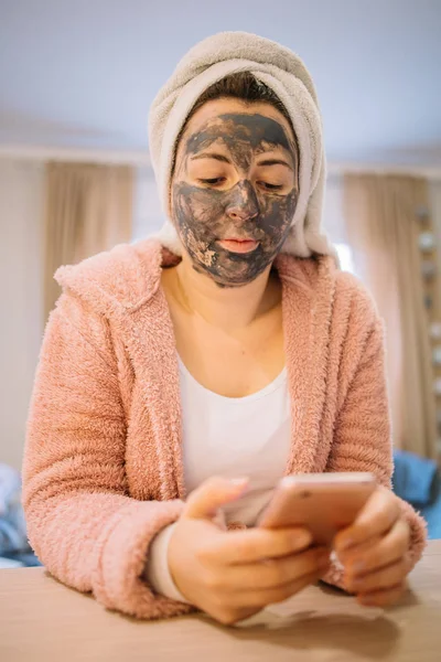 Woman using phone and having face mask — Stock Photo, Image