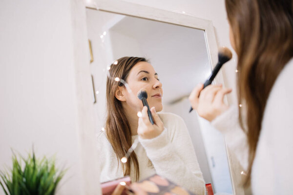 Woman contouring her face using brush and highlighters