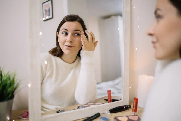 Chica preparándose para salir a maquillarse delante de un espejo — Foto de Stock