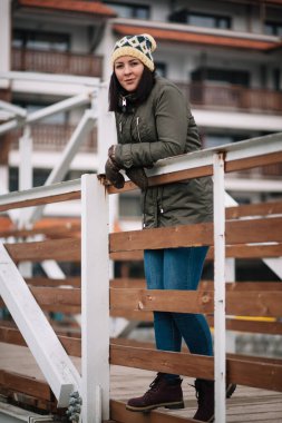 Kış elbiseli kadın köprüde duruyor.