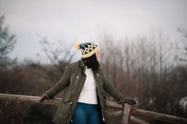 Dziewczyna z kapeluszem opierającym się na drewnianym ogrodzeniu — Zdjęcie stockowe