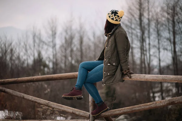 Туристична дівчина сидить на дерев'яному бар'єрі в горі — стокове фото