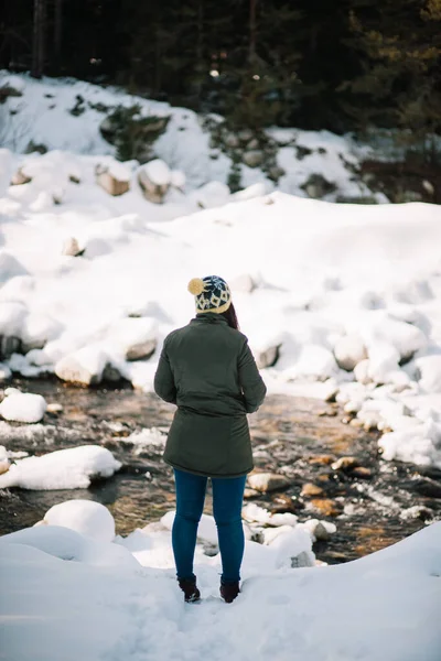 Back of a girl standing near winter river — 스톡 사진