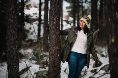 Smiling woman holding tree in the forest
