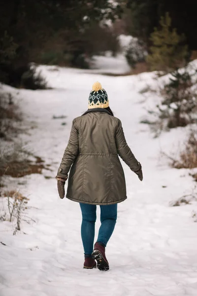 Back view of a woman walking on snowy road — 스톡 사진