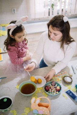 Mom take out egg from bowl with yellow paint
