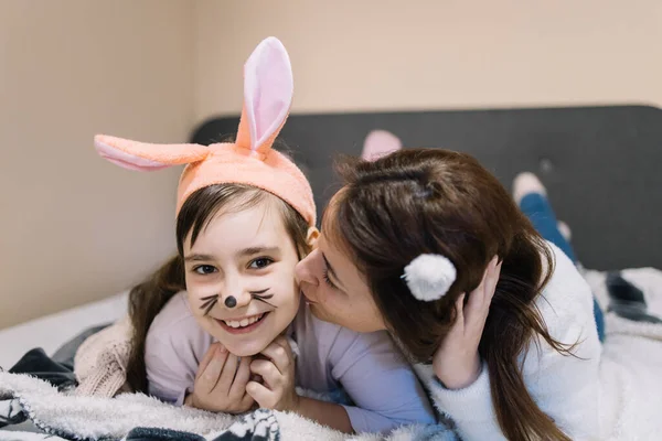 Mother kisses her little daughter with bunny ears