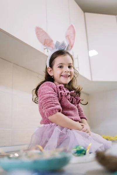 Cute little girl in bunny ears preparing for Easter holiday