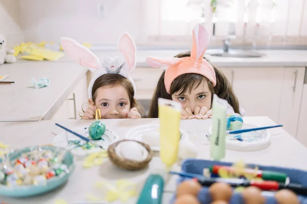 Two little girls hiding behind kitchen counter