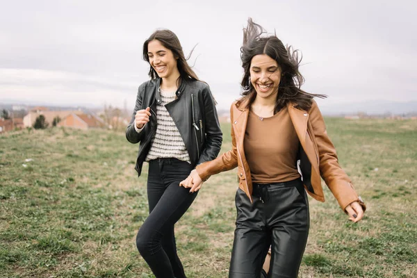 Twee meisjes die elkaars hand vasthouden en door een veld rennen — Stockfoto