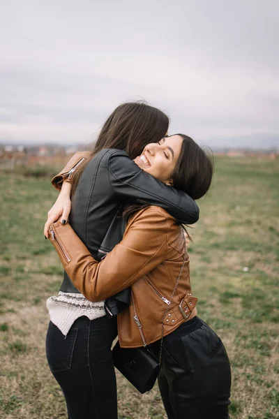 Attraktiv kvinna kramar sin kvinnliga vän på ett fält — Stockfoto