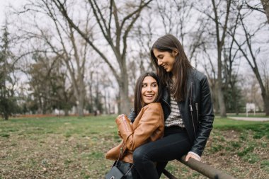 Gülümseyen kadın arkadaşlarının kucağına yaslanıyor.