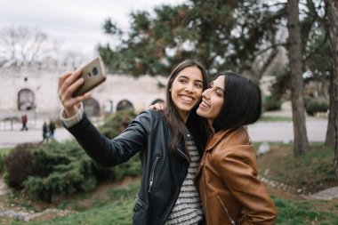 İkiz kardeşler gülümsüyor ve kendi fotoğraflarını çekiyorlar.