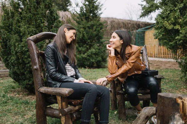 Две девушки смотрят друг на друга, сидя на деревянных стульях — стоковое фото