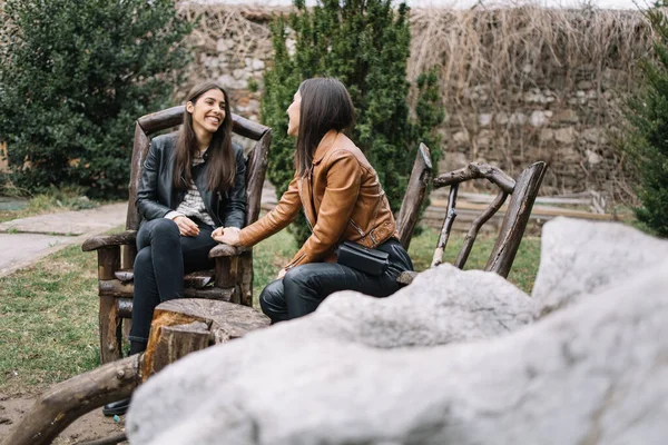 Brunette zussen hebben plezier in houten stoelen buiten — Stockfoto