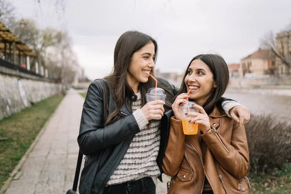 Chicas bebiendo jugo mientras caminan por la ciudad —  Fotos de Stock