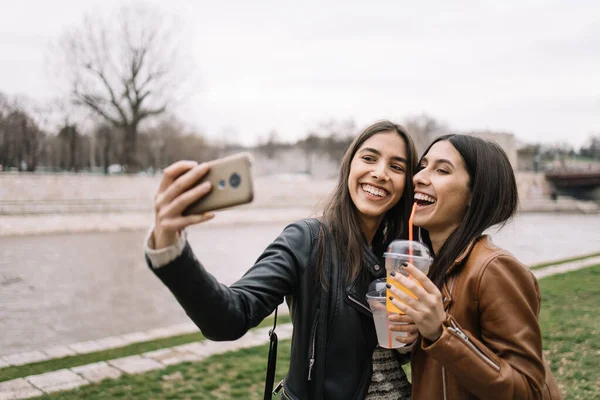 Glada kvinnor som gör selfie på flodstranden — Stockfoto