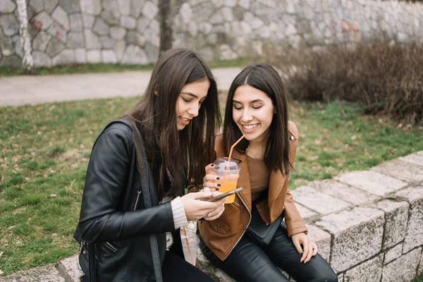 Hermosas chicas bebiendo jugo mientras están sentadas al aire libre —  Fotos de Stock
