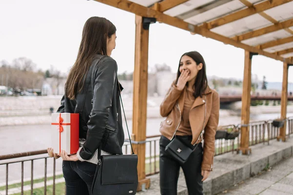 Fille cachant cadeau derrière son dos dans la rue — Photo