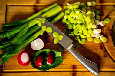 Kesme tahtasında ve bıçakta doğranmış yeşil sarımsak filizi.