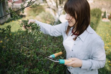 Çiçekçi kadın bahçe makası kullanarak tahta kesiyor.