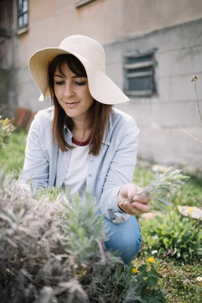Wanita Florist berjongkok di halaman dan merobek tanaman — Stok Foto