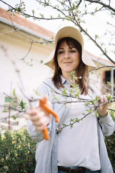 Happy woman holding cutting tool and trimming branches — Stok Foto