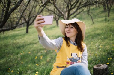Şapkalı kız bahçede selfie çekiyor.