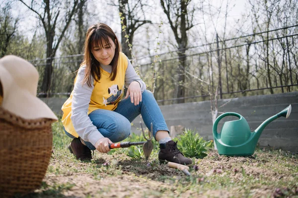 Wanita menggali dengan alat berkebun di halaman — Stok Foto