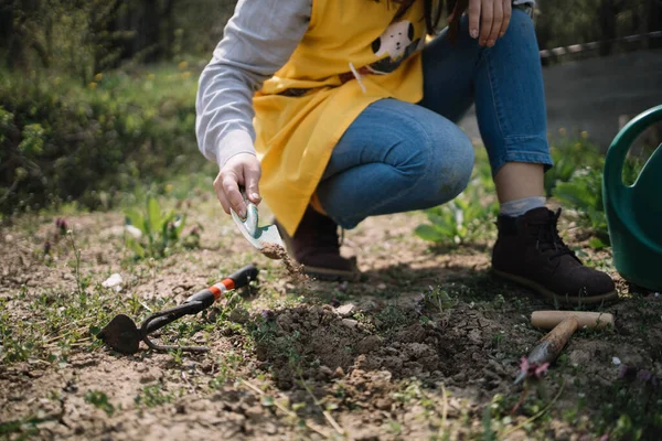 Wanita terpotong berjongkok di taman dengan alat tanam — Stok Foto