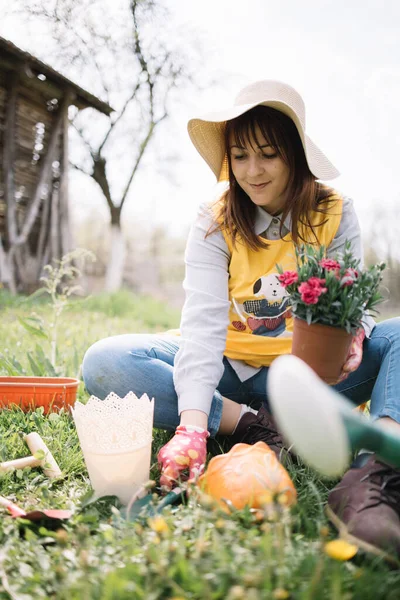 Wanita cantik menanam bunga sambil duduk di tanah — Stok Foto