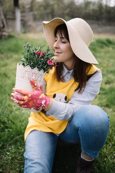Gadis dengan topi dan sarung tangan memegang pot putih dengan tanaman — Stok Foto