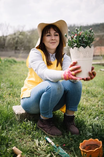 Wanita mengagumi pot dengan bunga di taman — Stok Foto