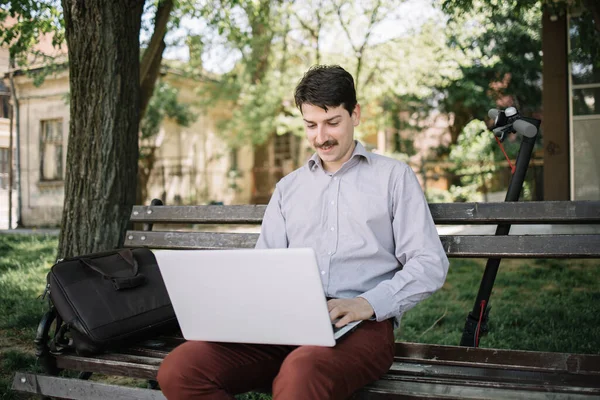 Freelancer masculino con bigote usando computadora en el parque — Foto de Stock