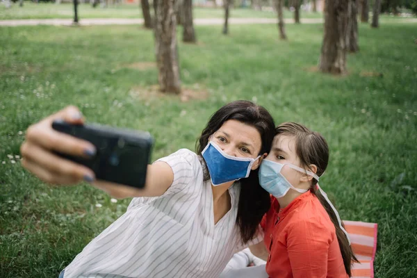 Portrait of girl and woman wearing masks in park