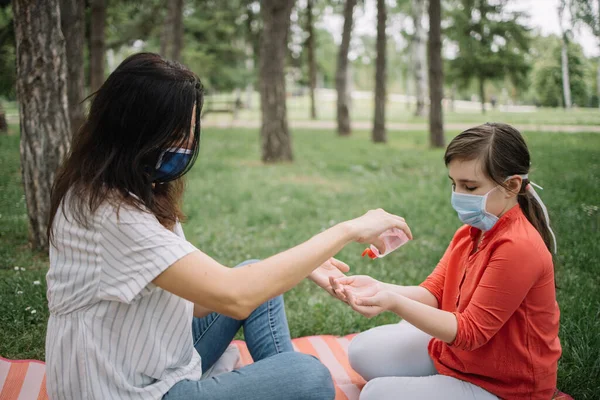 Maske takan ve el dezenfektanı kullanan kadın ve çocuğun yan görüntüsü