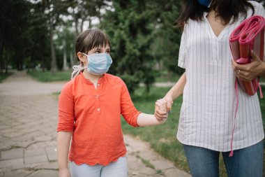 Maske takan ve parkta üzgün görünen bir çocuk portresi.