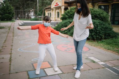 Genç bir kadın ve sevimli bir kız koruma maskesi takıyor.