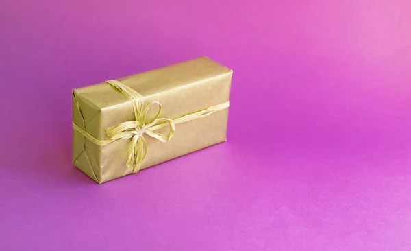 Golden box with a bow. Gift on a colored pink background. Great design for any purposes. Fashion, glamor background. New year, Christmas design.